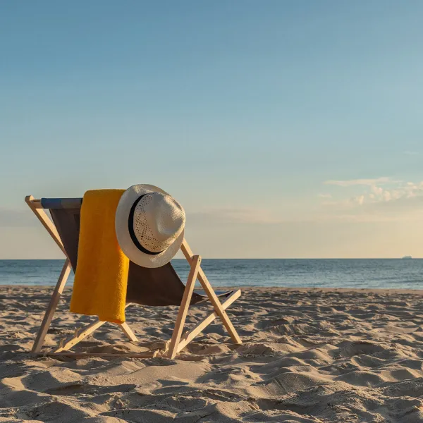 Ein gemütlicher Liegestuhl mit einem Sonnenhut und einem Handtuch am Ostseestrand in Binz bei sonnigem Wetter.