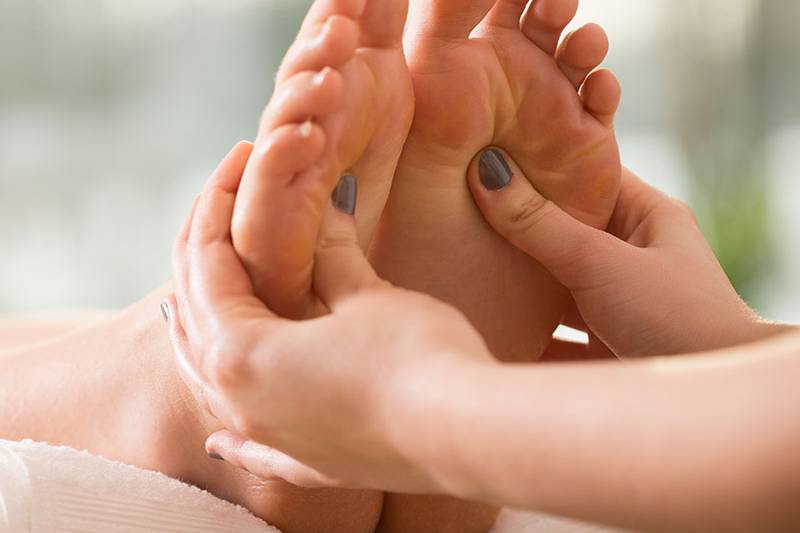 Die Füße einer Frau werden während einer Massageanwendung an der Ostsee massiert.