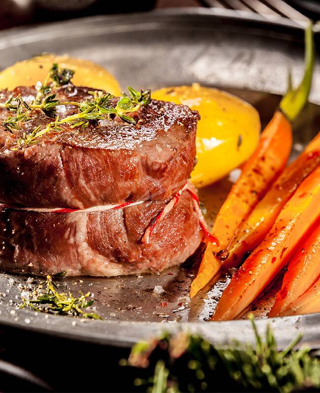 Ein saftiges Rinderfilet mit Gemüse und Kartoffeln angerichtet auf einem schönen Teller.