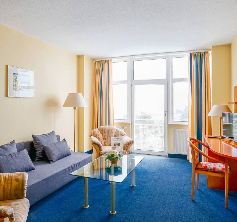 Suite im Arkona Strandhotel Binz mit Sitzecke, Glastisch und Blick auf den Balkon