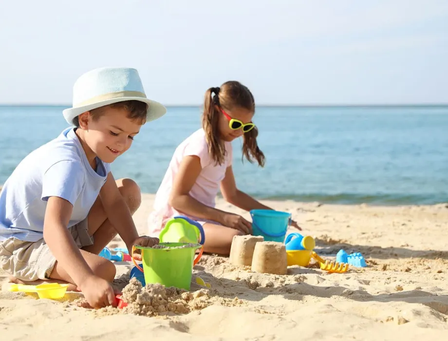 Kinder bauen Sandburgen am Strand von Rügen während eines Familienurlaubs.
