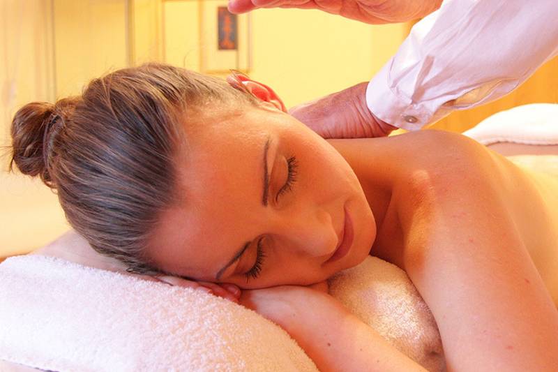 Frau liegt entspannt auf einer Liege und erhält eine klassische Rückenmassage im Arkona Strandhotel Rügen