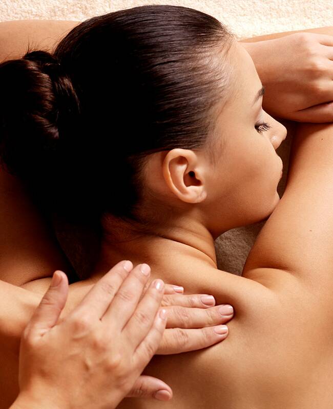Eine Frau liegt entspannt und mit geschlossenen Augen auf einer Massageliege und wird massiert.