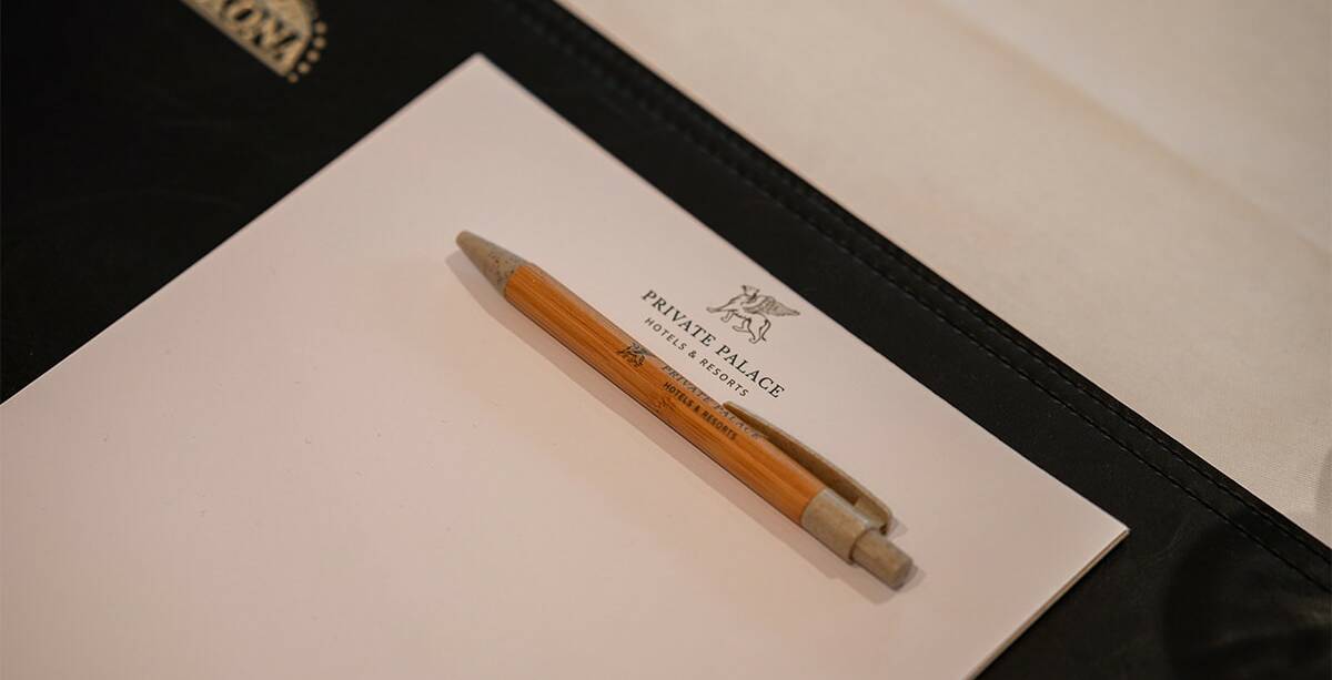 Nahaufnahme eines Stiftes und Papier mit Branding der Private Palace Hotels & Resorts.