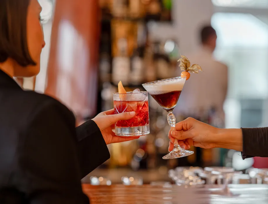 Guests toast with cocktails at the bar counter of the Arkona Bar on Rügen.