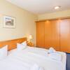 Hotelzimmer mit Doppelbett, Holzeinbauschrank und Nachttisch mit Lampe.