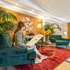 Eine Frau sitzt in einem Sessel in der Hotellobby und genießt die entspannte Atmosphäre beim Familienurlaub auf Rügen.