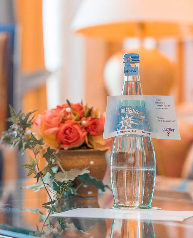 Eine Flasche Wasser und ein Strauß Blumen stehen zur Begrüßung im Spa- und Familienhotel auf Rügen.