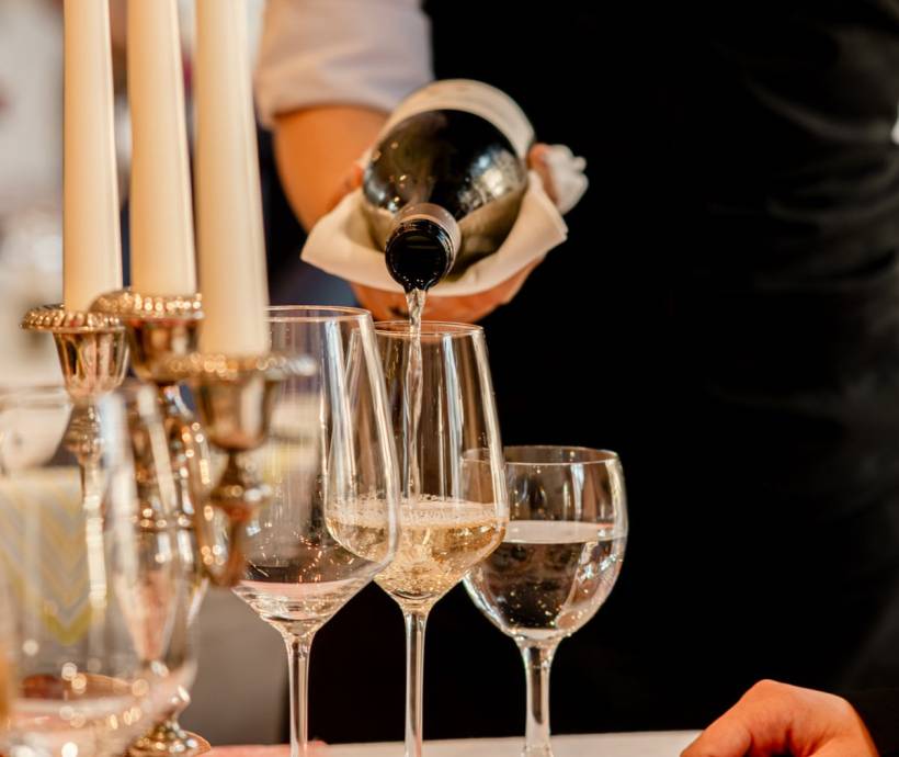 Ein Weinglas wird aufgefüllt bei einem festlichem Ambiente am Valentinstag im Familienhotel auf Rügen.