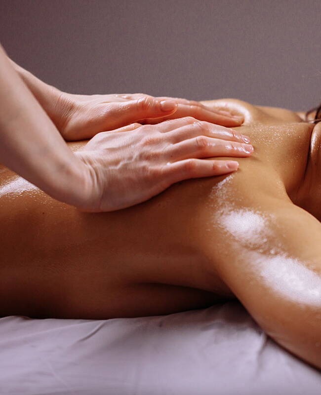 Eine Frau erhält eine Rückenmassage und entspannt sich dabei in einer ruhigen Umgebung.