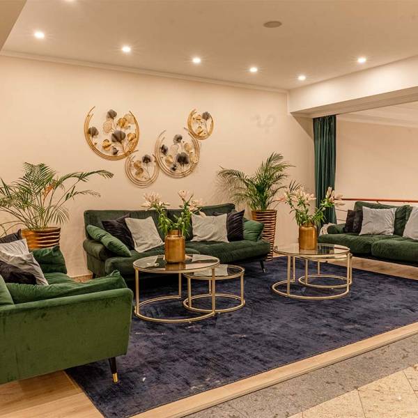 The inviting lobby of Arkona Strandhotel Binz featuring green velvet sofas, elegant decorations, and modern accents.