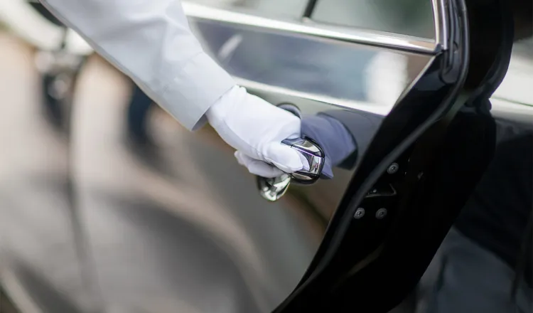 The chauffeur opens the door of the elegant limousine of the Arkona Strandhotel.