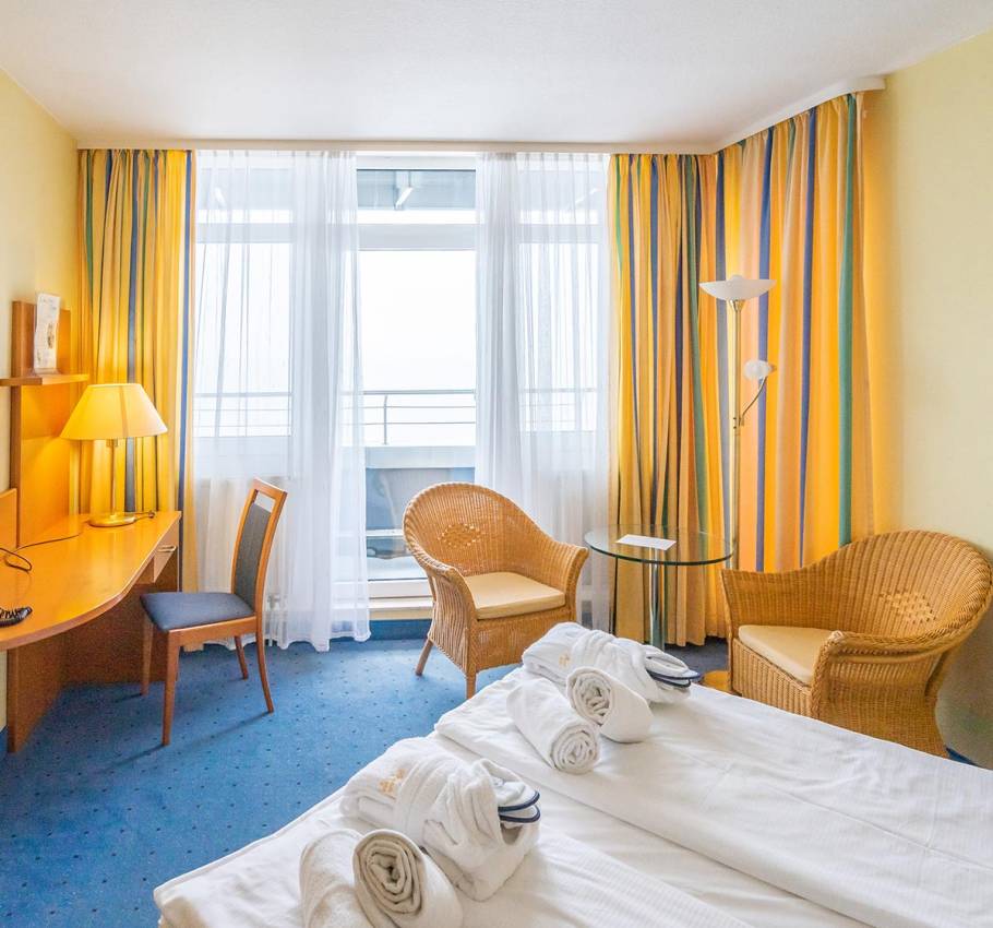 Doppelzimmer im Arkona Strandhotel Binz mit gemütlicher Sitzecke, Schreibtisch und Zugang zum Balkon mit Meerblick.