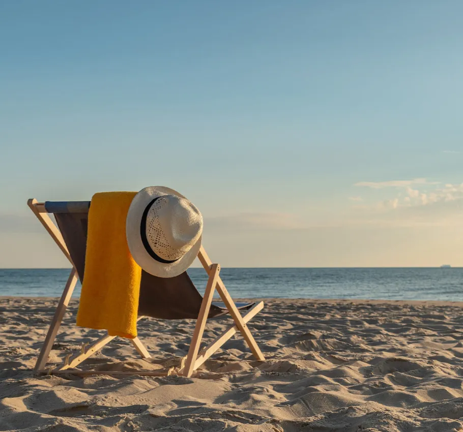 A cozy deck chair with a sun hat and a towel on the Baltic Sea beach in Binz in sunny weather.