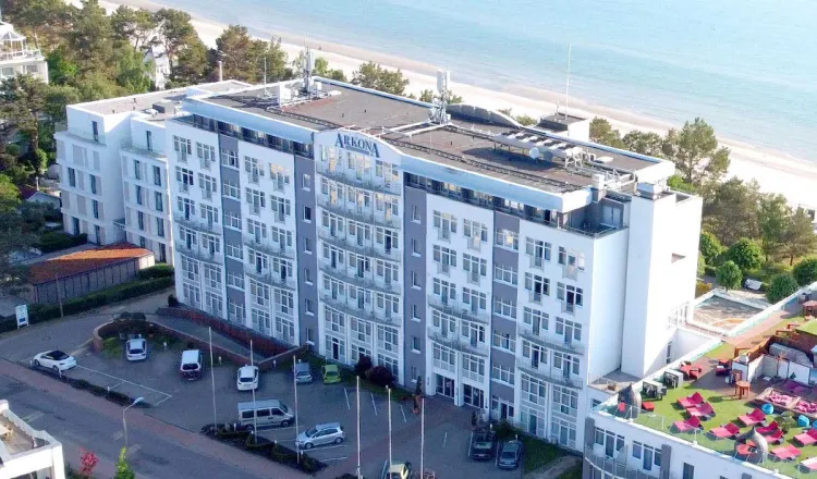 Aufnahme aus der Luft des Arkona Strandhotel direkt am Meer, im Hintergrund Bäume und der Strand.