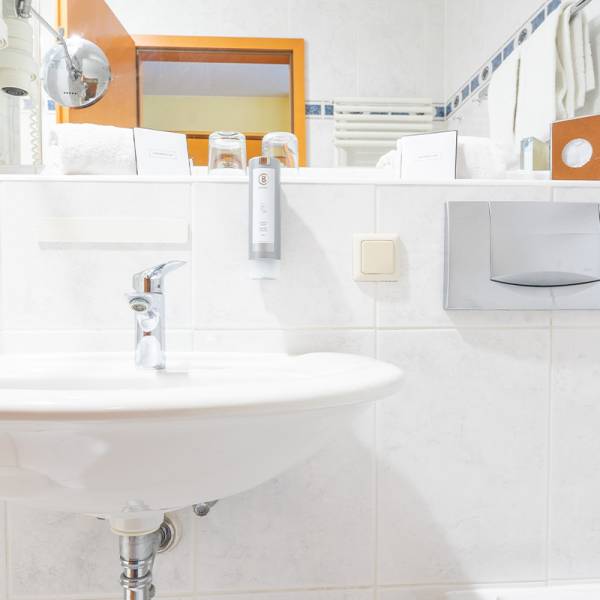 Bathroom at Arkona Strandhotel featuring a white sink, mirror, and bathroom accessories.