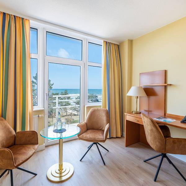 Sitting area in the double room of Arkona Strandhotel Binz with table, armchairs, and a view of the Baltic Sea.