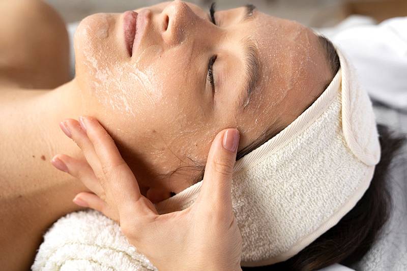 Eine Frau mit geschlossenen Augen erhält eine Gesichtsbehandlung mit Peeling im Arkona Strandhotel Rügen
