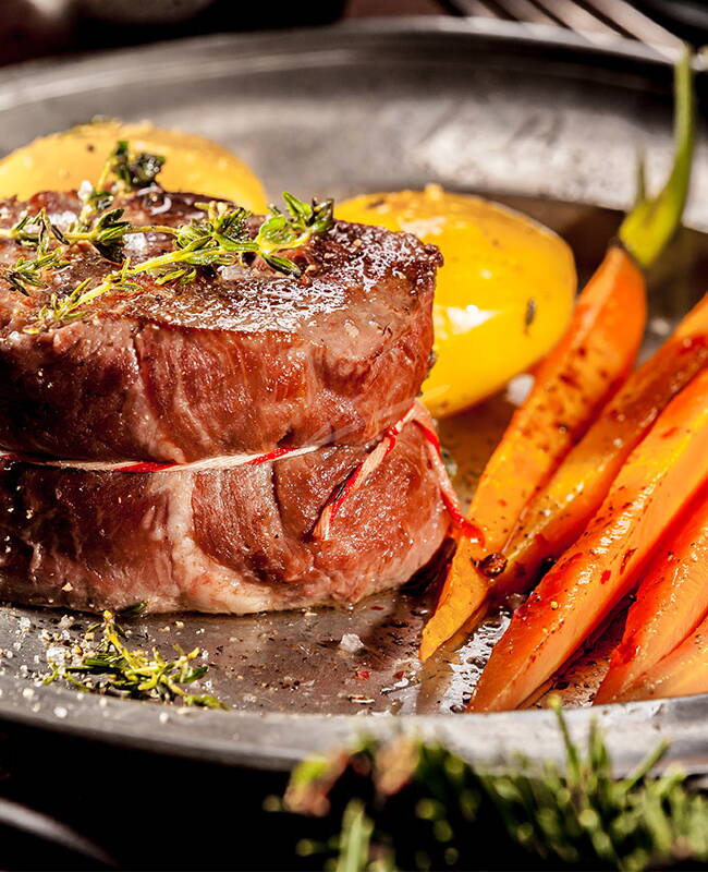Ein saftiges Rinderfilet mit Gemüse und Kartoffeln angerichtet auf einem schönen Teller.