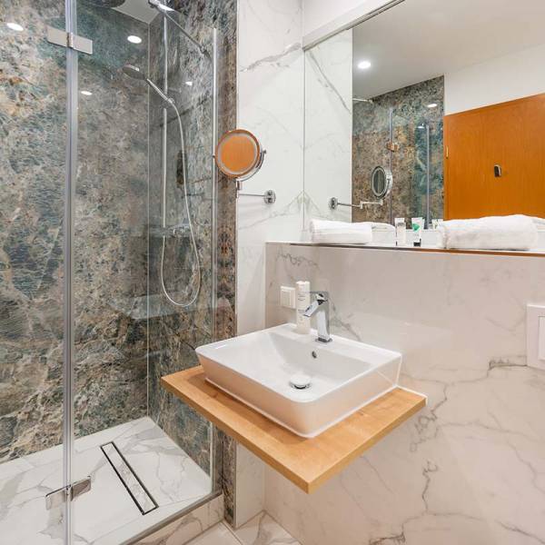 Bathroom at Arkona Strandhotel Binz with a spacious shower, sink, and stylish marble walls.
