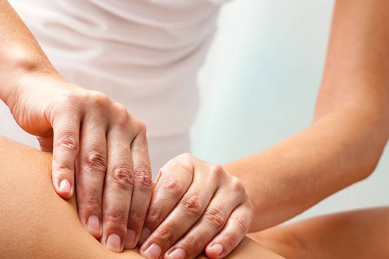 Eine Frau wird von einer Masseurin im Arkona Strandhotel am Körper massiert.