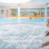 Eine Frau sitzt im sprudelnden Whirlpool im Wellnessbereich eines Hotels.