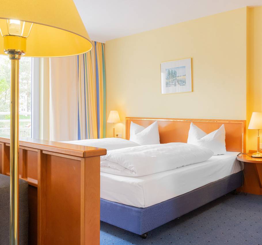 Junior Suite im Arkona Strandhotel Binz mit Doppelbett, gemütlicher Beleuchtung und Blick auf die Stadt.