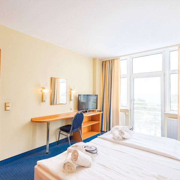Sea view suite at Arkona Strandhotel Binz featuring a double bed, desk, and TV