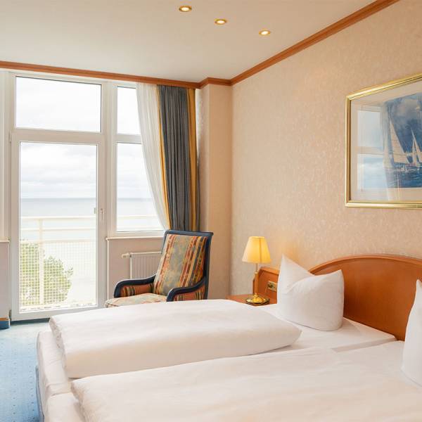 The cozy double bed in the presidential suite at Arkona Strandhotel Binz with a balcony and a view of the Baltic Sea