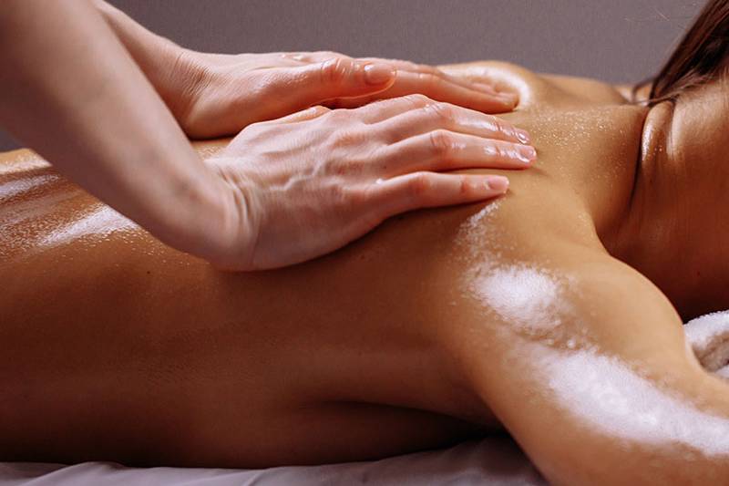 Eine Frau liegt auf ihrem Bauch und genießt ein Meersalzpeeling im Wellnesshotel Arkona Strandhotel.
