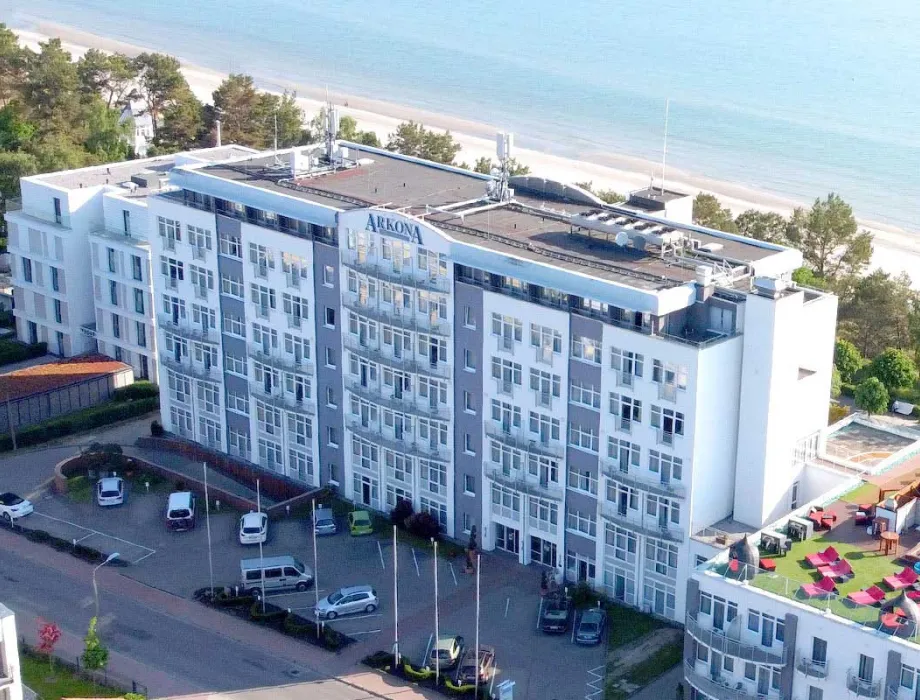 Aufnahme aus der Luft des Arkona Strandhotel direkt am Meer, im Hintergrund Bäume und der Strand.