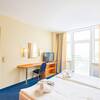 Hotelzimmer mit Doppelbett, Schreibtisch, Fernseher, Fenster mit Vorhängen und Meerblick.