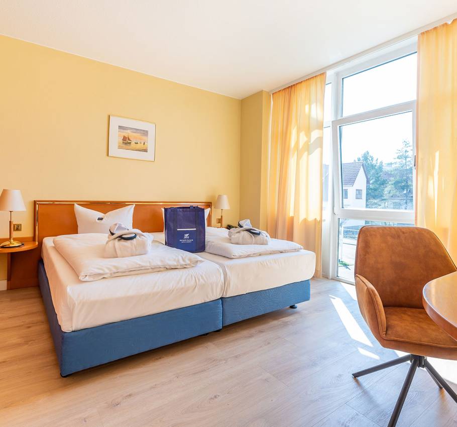 Helles und freundliches Doppelzimmer in der Suite des Arkona Strandhotels Binz mit großen Fenstern, Doppelbett und bequemen Sesseln.