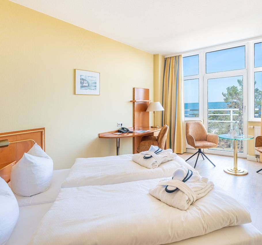 Doppelzimmer im Arkona Strandhotel Binz mit zwei Einzelbetten, Meerblick und gemütlicher Sitzecke.