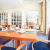 Der Frühstücksraum des Arkona Strandhotels für Familienurlaube auf Rügen, mit hölzernen Tischen und blau bezogenen Stühlen.