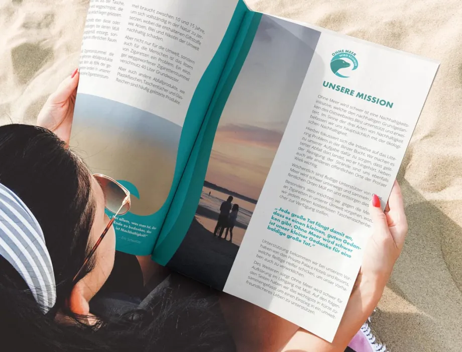 Frau liest das OMWS-Magazin am Strand von Binz – Arkona Strandhotel engagiert sich mit der Initiative „Ohne Meer wird schwer“ für Umweltschutz