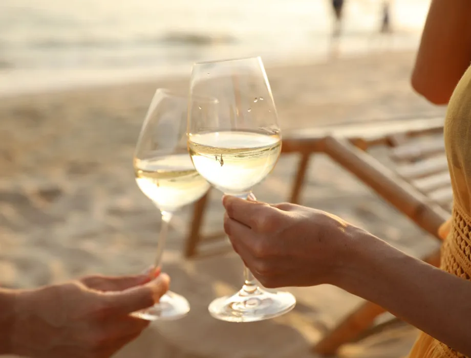 Paar stößt mit Weißwein am Strand von Binz an – Teil des Green Stay-Programms im Arkona Strandhotel auf Rügen