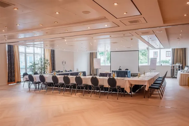 Tagungsraum mit U-förmiger Bestuhlung, Beamer-Leinwand, großen Fenstern und moderner Beleuchtung im Arkona Strandhotel in Binz.