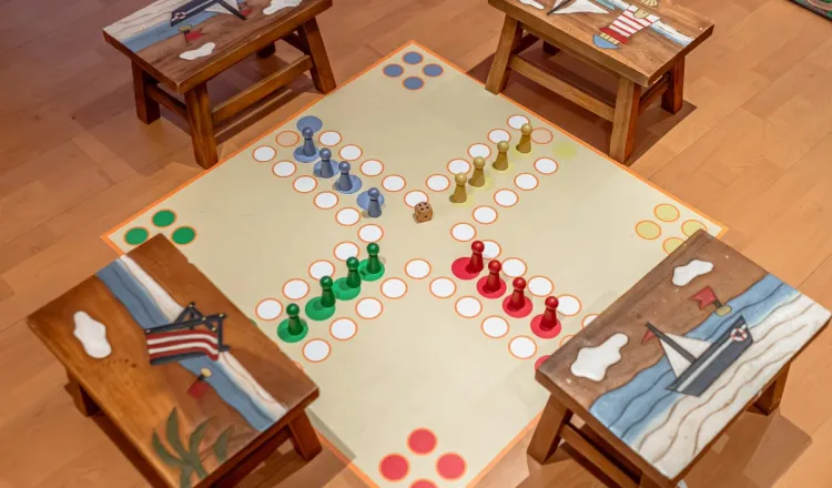 A large Ludo board with little stools for the children fun on a family vacation at the Baltic Sea.