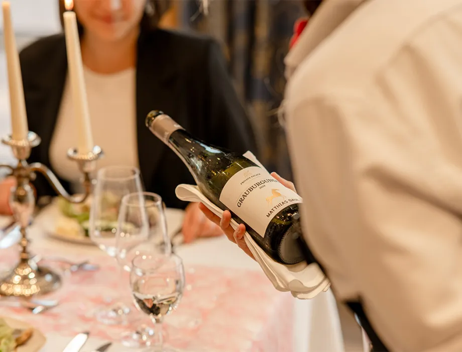 Waiter pours Pinot Gris wine into a wine glass at a carefully decorated table in the Rossini restaurant on the Baltic Sea.