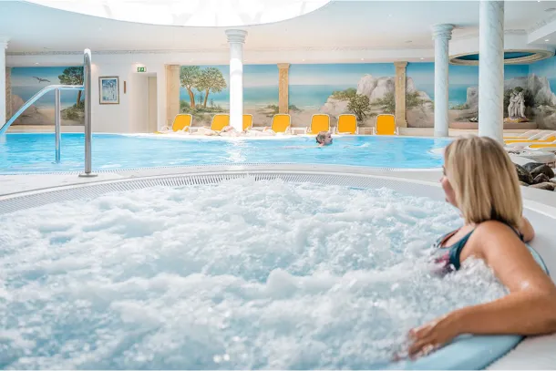 Eine Frau sitzt im sprudelnden Whirlpool im Wellnessbereich während einer Tagung im Arkona Strandhotel in Binz auf Rügen.