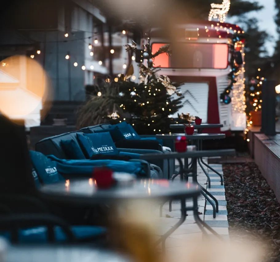 Cozy hotel terrace decorated with Christmas lights, festive ornaments and comfortable seating during the holiday season.