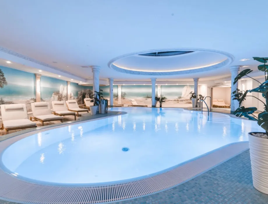 Großer Innenpool im Arkona Strandhotel Binz auf Rügen mit Liegen, Säulen und hellem Wellnessbereich