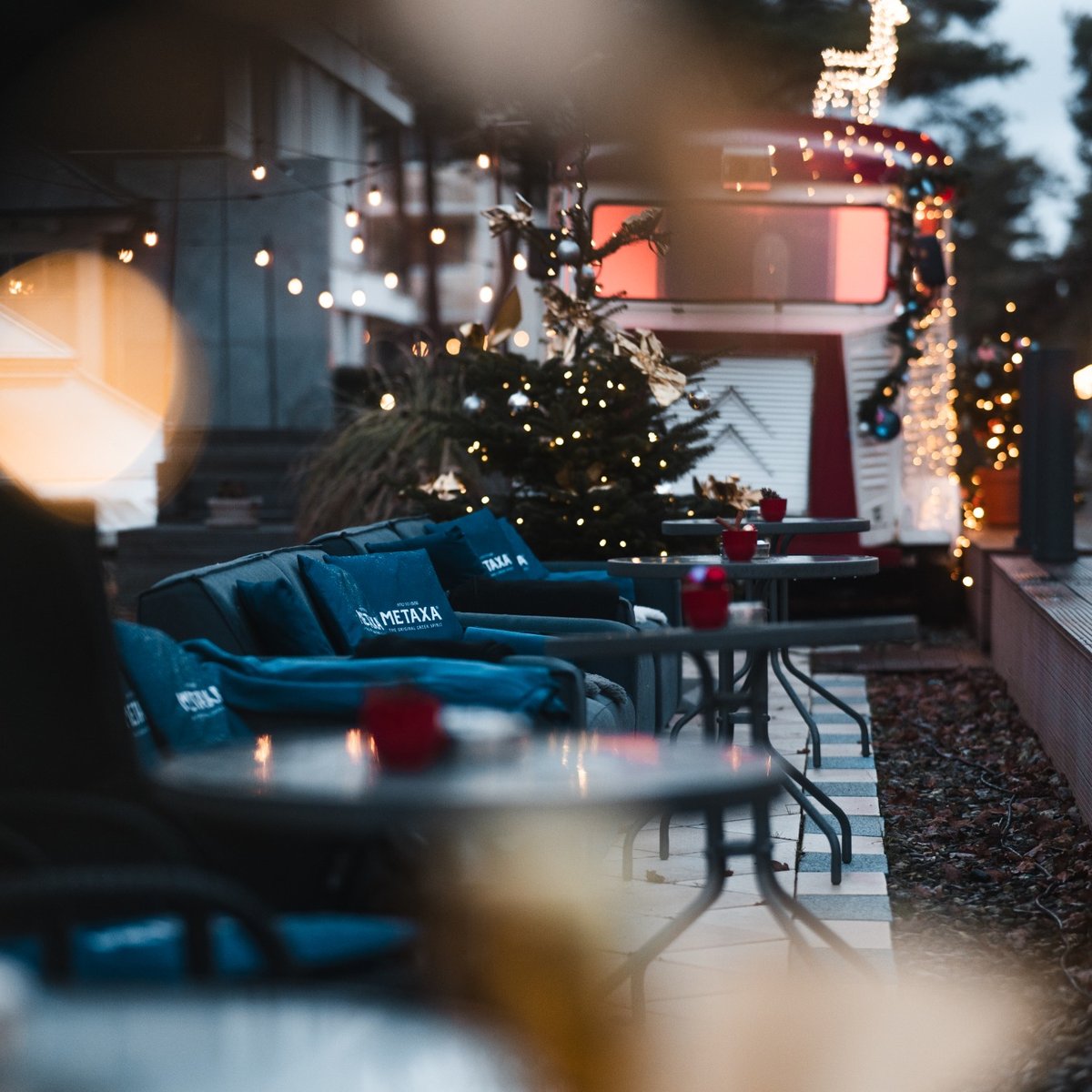 Cozy hotel terrace decorated with Christmas lights, festive ornaments and comfortable seating during the holiday season.