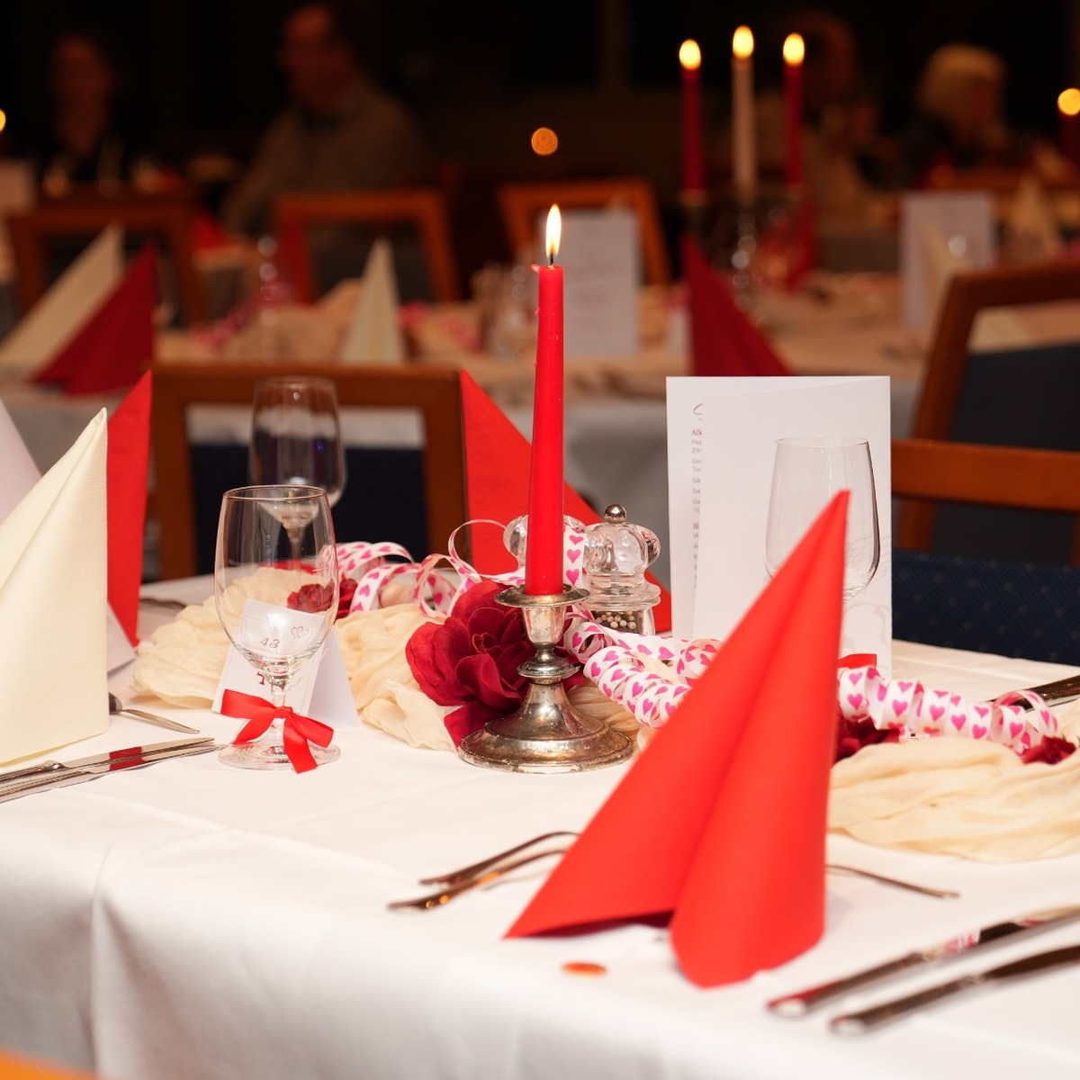 Romantisch gedeckter Tisch mit roter Kerze, Herzdekoration und roten Servietten zur Valentinstag-Party im Arkona Strandhotel in Binz.