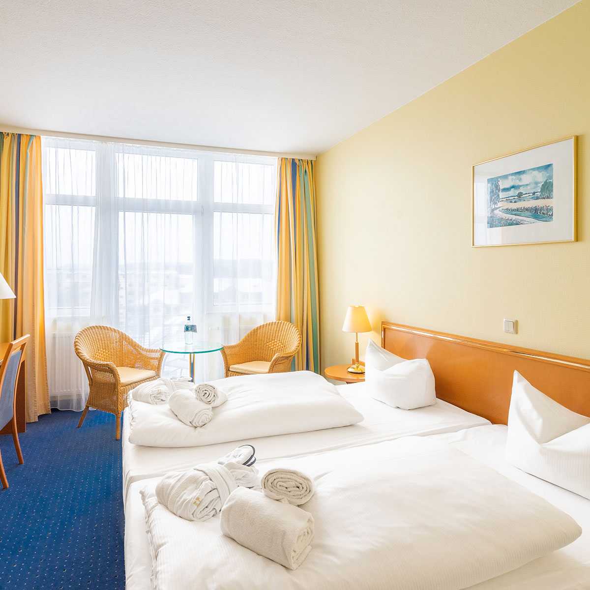 Ein frisches weiß bezogenes Hotelbett in einem Zimmer mit gelben Wänden,