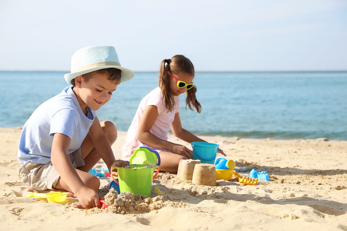 Kinder bauen Sandburgen am Strand der Ostsee während des Sommerurlaubs