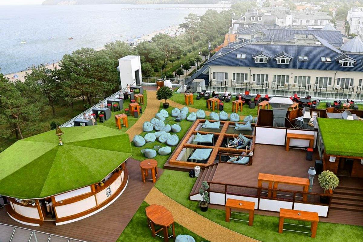 Aufnahme von oben von der Terrasse des Hotels mit grünem Gras, Sitzsäcken und verschiedenen Sitzecken.