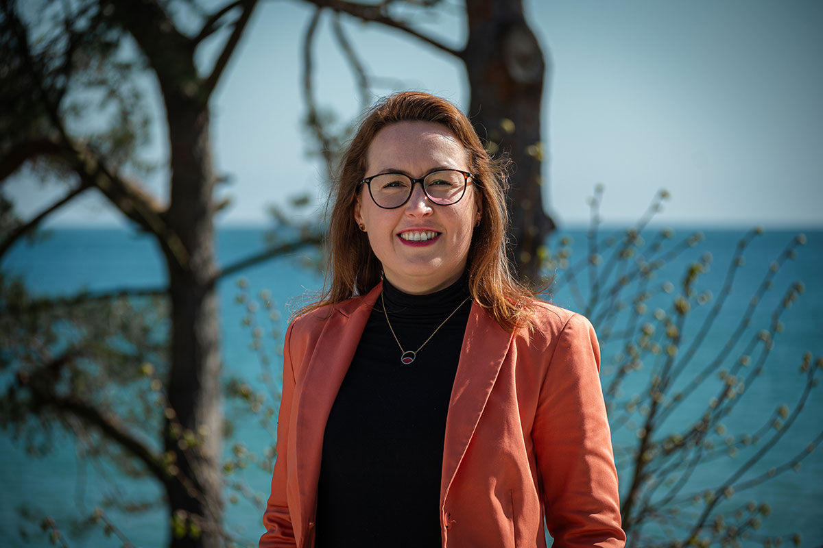 Dorothee Schicht am Strandübergang in Binz bei Sonne – Executive Assistant im Arkona Strandhotel und tragende Stütze im Hintergrund