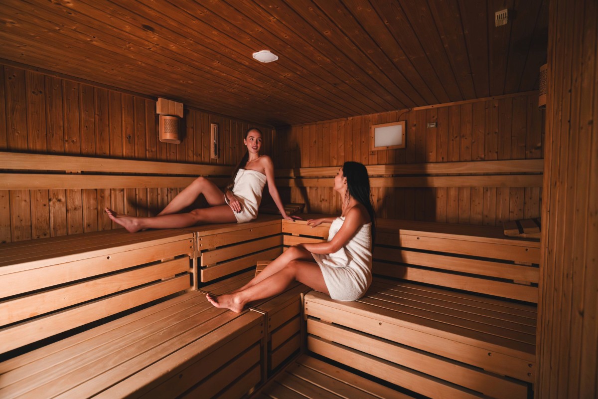 Two women sitting in the sauna at Arkona Strandhotel Binz on Rügen on wooden benches